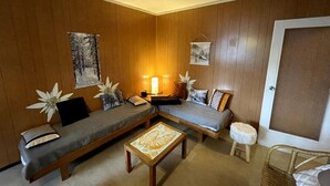 Una habitación acogedora con paredes de madera, un sofá, una mesita y una silla.