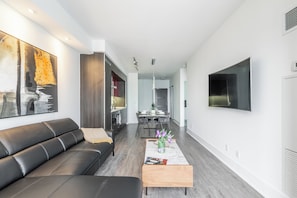 A modern living room with a black leather sofa, a wooden coffee table, and a large abstract painting on the wall. - Aera Toronto - The Entertainment District (Toronto)