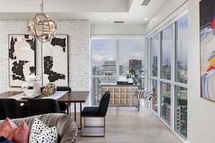 Una sala moderna con comedor, ventanas amplias y vistas a la ciudad.