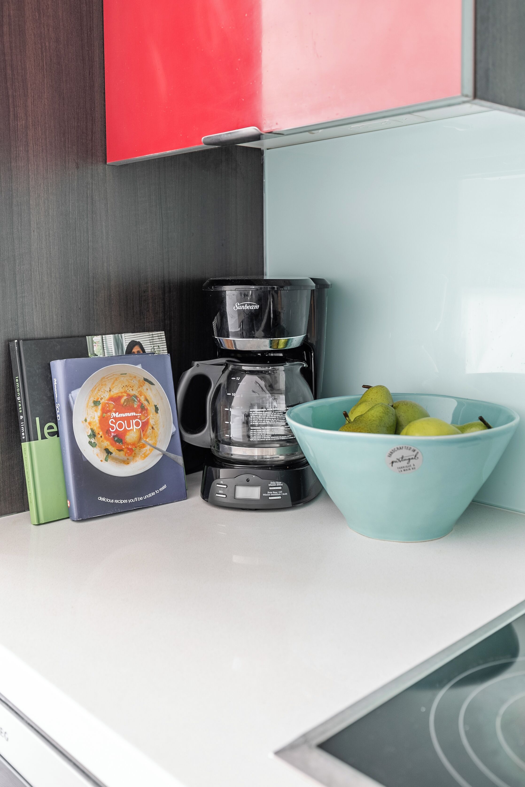 Een keukentrap met een koffiezetapparaat, een schaal fruit en een kookboek.