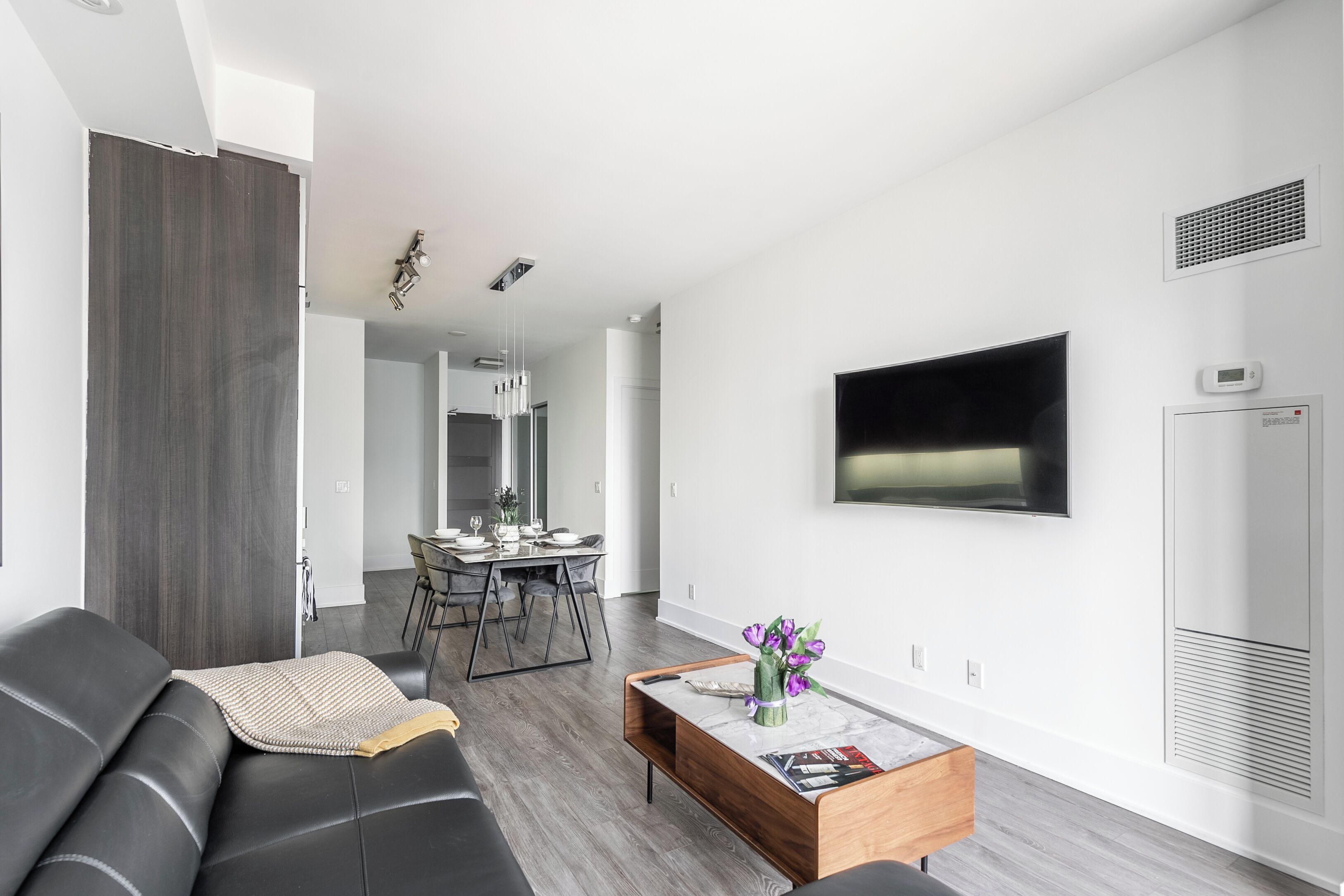 A modern living room with a sofa, coffee table, and a flat-screen TV mounted on the wall.