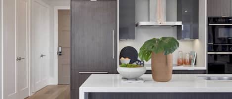 A modern kitchen with dark wood cabinets, a white countertop, and a central island with stools.