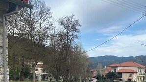 Un banc de pedra amb estructura metàl·lica, una paret de pedra i una taula petita amb un ram de flors.