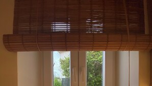 Habitació amb una porta corredissa de vidre que dona a una zona exterior, una petita finestra amb una barana metàl·lica i una paret de pedra a l'exterior.
