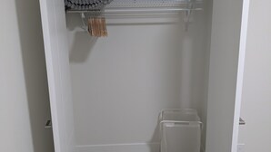 Un vestidor con piso de madera, una barra para colgar ropa y un contenedor de almacenamiento.