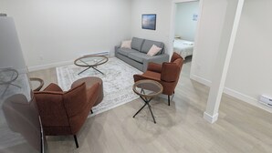 Una sala moderna con un sofá gris, sillones marrones y una mesa de centro redonda.