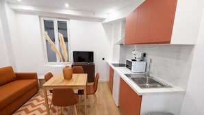 Ett kompakt bostadsutrymme med en matplats, ett litet kök och en soffa.
