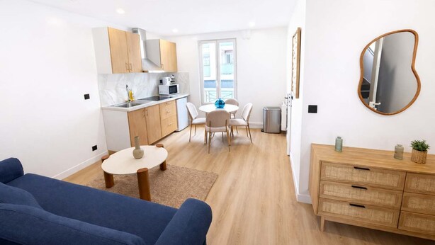 A compact living space with a kitchenette, dining area, and a sofa. - Appartement Cosy a Aubervilliers - 4P (Aubervilliers)