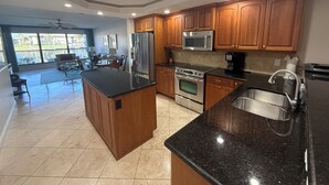 A modern kitchen with wooden cabinets, stainless steel appliances, and a large island. - Cape coral/Fort Myers: First floor condo on wide canal next to Jaycee park (Cape Coral)