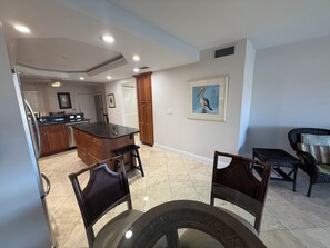 A spacious living area with a kitchen, dining table, and two chairs. - Cape coral/Fort Myers: First floor condo on wide canal next to Jaycee park (Cape Coral)