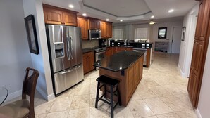 A modern kitchen with stainless steel appliances, wooden cabinets, and a central island. - Cape coral/Fort Myers: First floor condo on wide canal next to Jaycee park (Cape Coral)