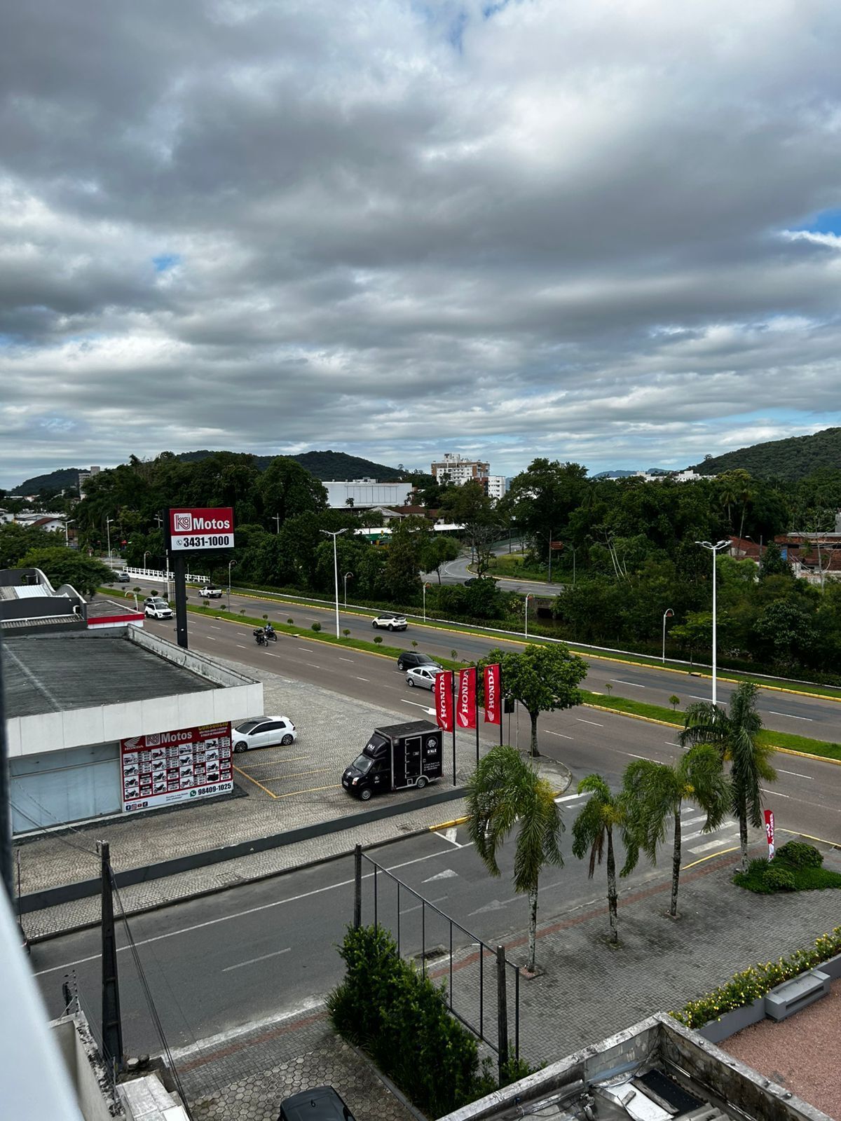 Zona comercial con un cartel grande que dice 'Motos' y varias banderas de Honda.