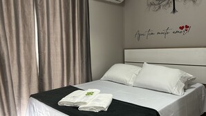 A hotel room with a bed, white linens, a black throw blanket, and two towels on the bed. - AP ENCANTADOR 1 QUARTO PX. DO CAU HANSEN (Joinville)