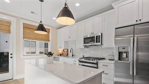 Una cocina moderna con armarios blancos, electrodomésticos de acero inoxidable y una isla central.
