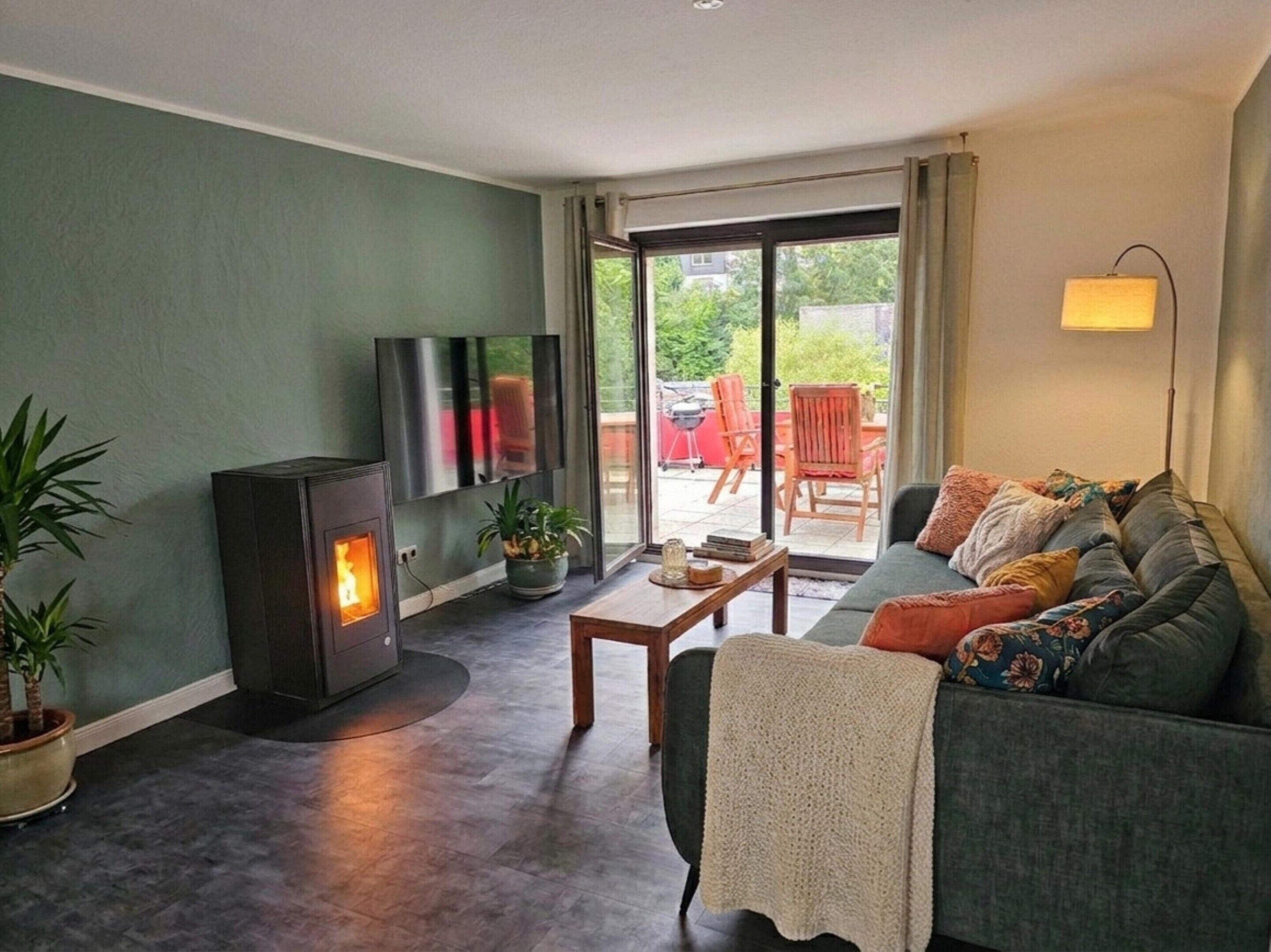 A living room with a fireplace, sofa, TV, and a sliding glass door leading to an outdoor area.