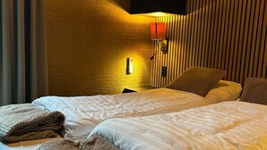 A hotel room with two beds, a nightstand, a lamp, and a textured wall. - Romantic Getaway at Drenthe Nature Lodge (Dalerveen)