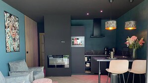 A modern living room with a grey sofa, a pink ottoman, and a herringbone floor. - Romantic Getaway at Drenthe Nature Lodge (Dalerveen)