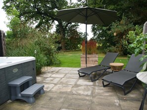 An outdoor patio with a hot tub, lounge chairs, and a wooden planter. - Romantic Getaway at Drenthe Nature Lodge (Dalerveen)