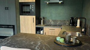 A modern kitchen with a marble countertop, a built-in microwave, a stainless steel sink, and a small coffee station. - Romantic Getaway at Drenthe Nature Lodge (Dalerveen)