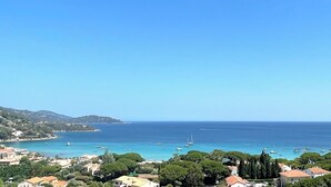 A coastal town with buildings along the shoreline, boats in the water, and a clear blue sky. - 🌅 ST CLAIR  LAVANDOU  EXCEPTIONAL PENTHOUSE  TOP FLOOR  180° PANORAMIC SEA VIEW (LE LAVANDOU)