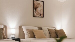 Hotellihuone, jossa on kaksi sänkyä, yöpöytä, lamppu ja seinällä oleva taideteos.