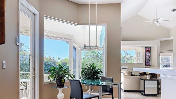 A modern kitchen with a glass dining table, chairs, and a potted plant. - Butterfly House – Organic Garden Retreat in Popular Golf Community (Sarasota)
