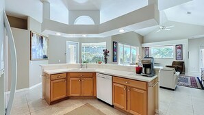 A modern kitchen with a large island, built-in appliances, and large windows offering views of the outdoors. - Butterfly House – Organic Garden Retreat in Popular Golf Community (Sarasota)
