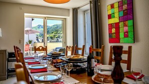 A dining area with a table set for four, a bottle of wine, and a colorful artwork on the wall. - Estate With Panoramic Sancy Views (Mont-Dore)