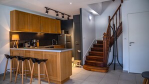 A modern kitchen with wooden cabinets, a central island with stools, a microwave, and a refrigerator. - Estate With Panoramic Sancy Views (Mont-Dore)