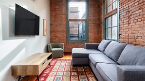 A modern living room with a large gray sectional sofa, a wooden coffee table, a green armchair, and a patterned rug. - Block House (Vancouver)