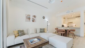 Ein modernes Wohnzimmer mit einer Eckcouch, einem Holztisch und einem Essbereich mit Stühlen.