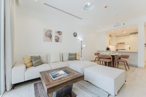 Een moderne woonkamer met een modulaire bank, een houten salontafel, en een eethoek met stoelen.