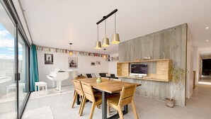 Ein stilvoller Essbereich mit Holztisch und Stühlen, einem Klavier und einem Bücherregal mit Büchern und gerahmten Bildern.