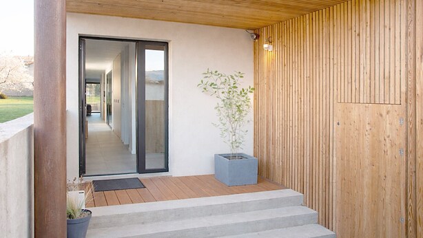 Ein modernes Äußeres mit einer Holzlamellenwand, einer Betonstufen und einem Blumentopf.
