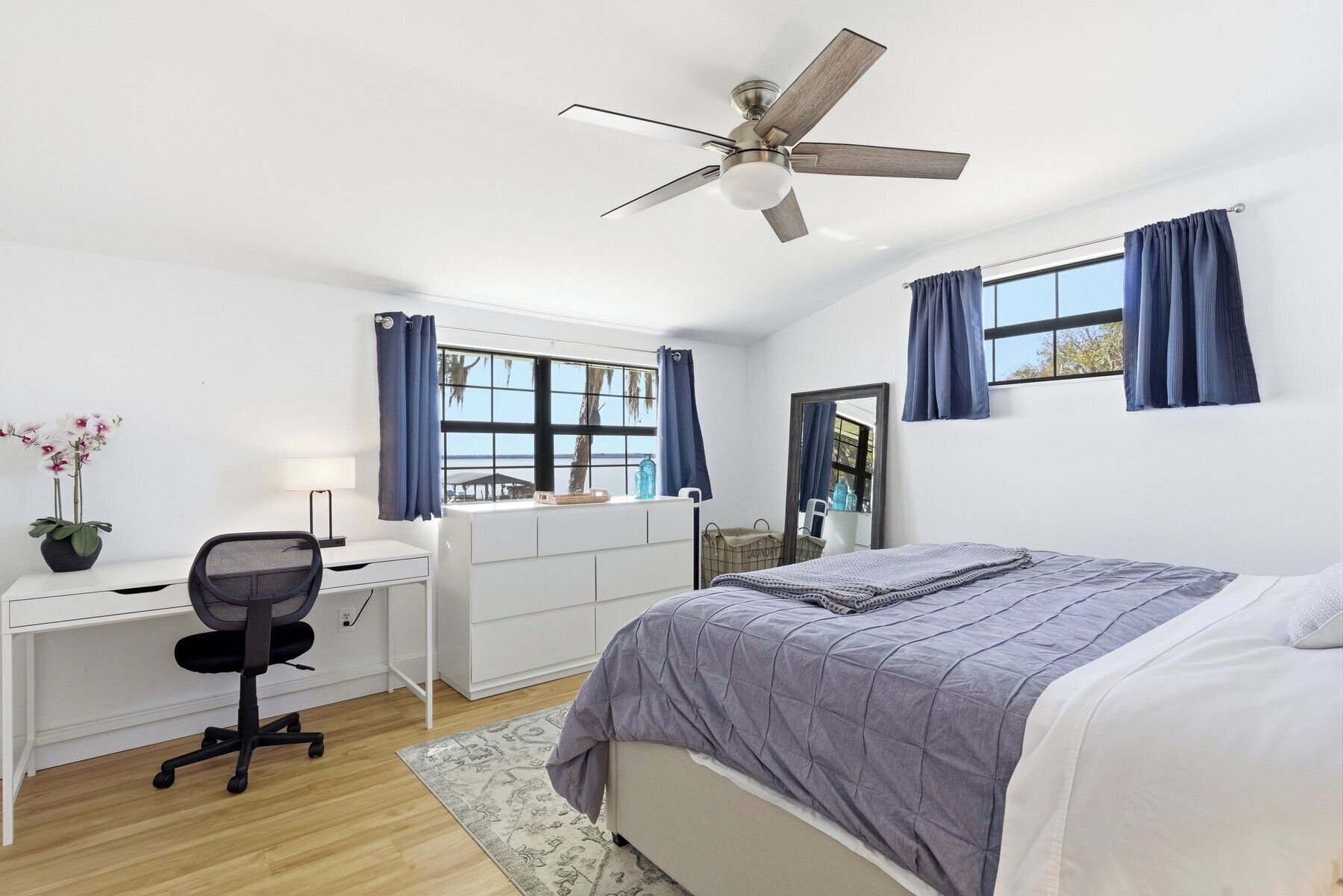 Une chambre à coucher comprenant un lit, un bureau, une chaise et un ventilateur de plafond.