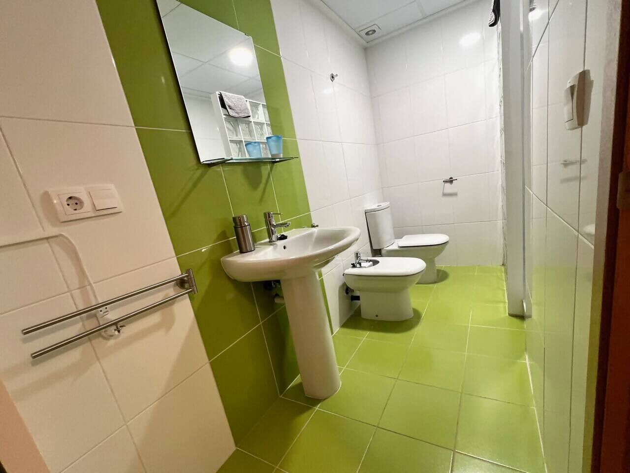 A bathroom with a sink, toilet, and a mirror.