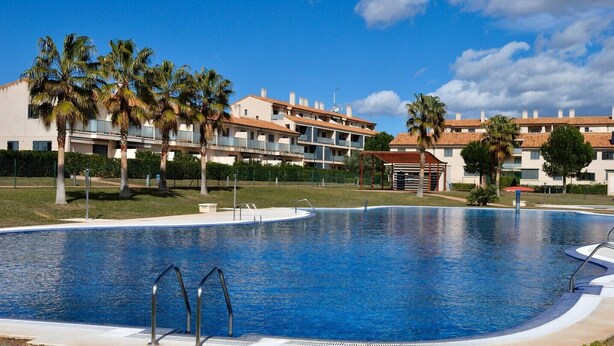 A swimming pool with a clear blue water, surrounded by a grassy area and palm trees. - Sol, Golf & Relax – Luxury house golf & sea (San Jorge)