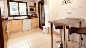 A modern kitchen with a dining area, a microwave, a sink, and a clock on the wall. - Sol, Golf & Relax – Luxury house golf & sea (San Jorge)
