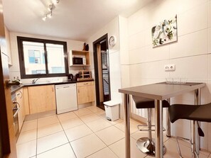Una cocina moderna con comedor, microondas, fregadero y un reloj en la pared.
