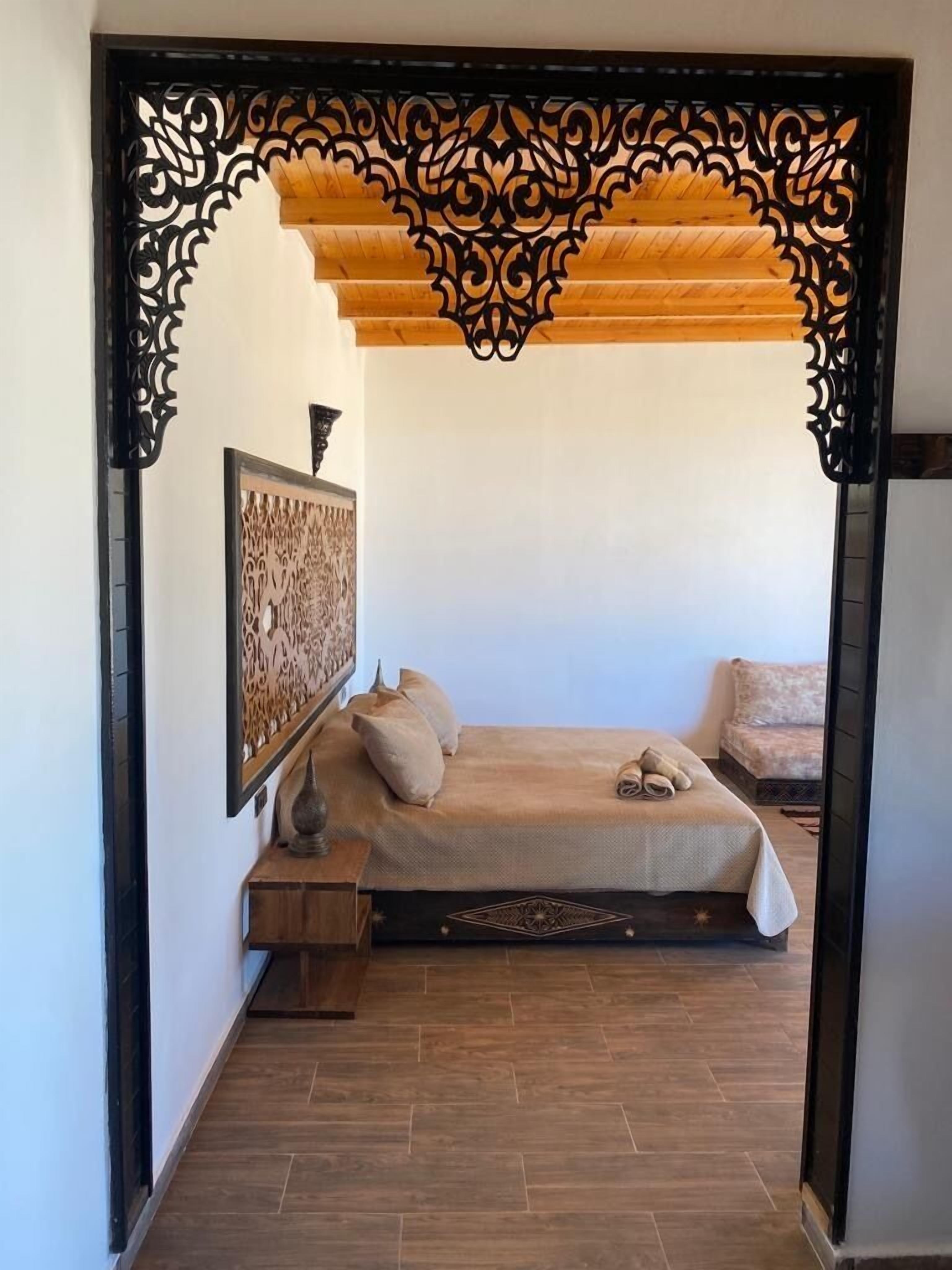 A bedroom with a bed, pillows, a nightstand, and a decorative wall piece.