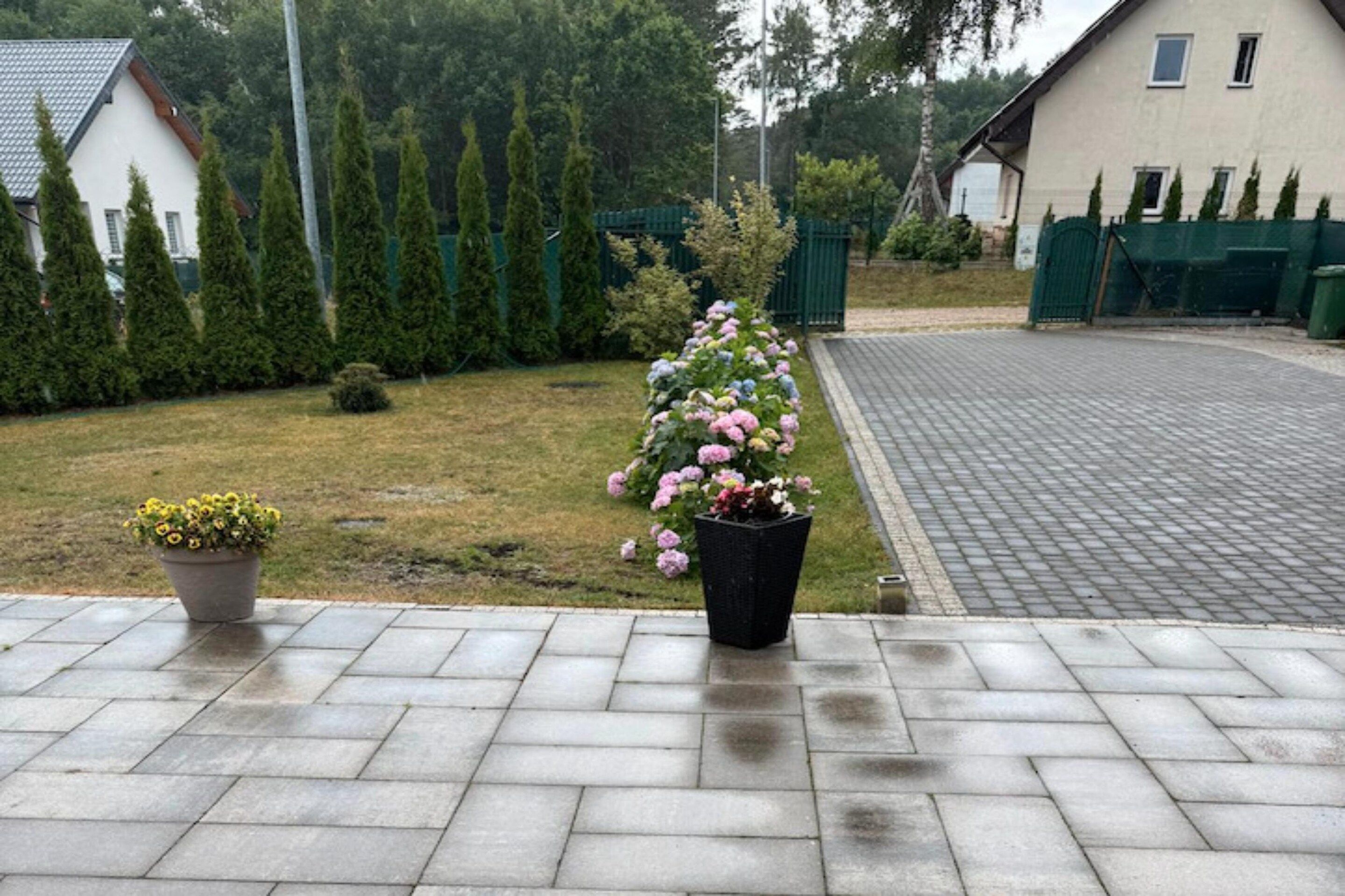 Une allée pavée mène à une maison dont le jardin se trouve au premier plan.