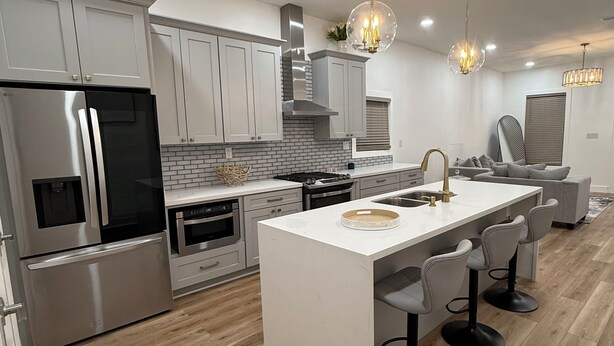 A modern kitchen with stainless steel appliances, a white island with bar stools, and pendant lighting. - Modern 3BR Family Home - Large Backyard, Kid-Friendly, Minutes from Downtown! (New Orleans)