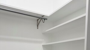 A white closet with multiple shelves and a metal rod for hanging items. - Modern 3BR Family Home - Large Backyard, Kid-Friendly, Minutes from Downtown! (New Orleans)