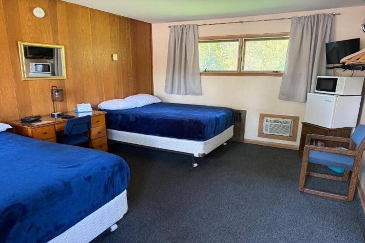 A room with two beds, a desk with a chair, a television, and a microwave.