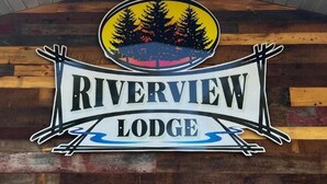Letrero de Riverview Lodge con un logotipo circular que muestra una escena de bosque y un cartel con el nombre del alojamiento.
