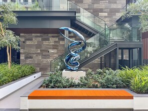 Un edificio moderno con una escalera de cristal, una escultura de metal y un cartel que indica un gimnasio.
