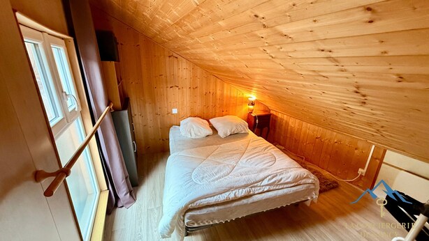 Et hyggeligt soveværelse på loftet med trævægge og skråt loft.