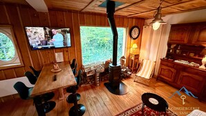 Ein gemütliches Blockhaus-Interieur mit einem Holzespeisesaal, Stühlen, einem Fernseher, einem Kamin und einer Küchenzeile.