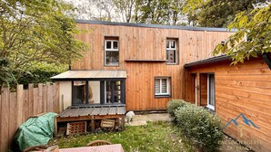 Ein Holzhaus mit umzäuntem Garten, einem kleinen Tisch und einem überdachten Bereich.