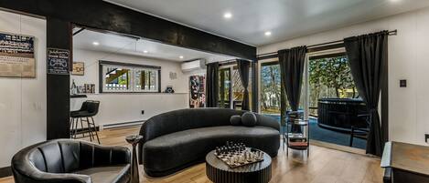 A modern living room with a curved sofa, a chess table, and a bar area.